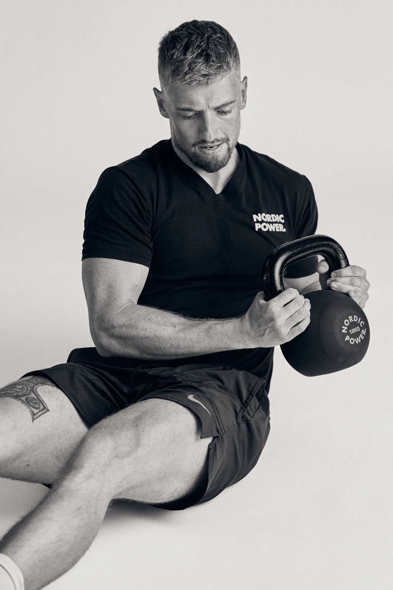 Mand træner siddende med kettlebell i studie
