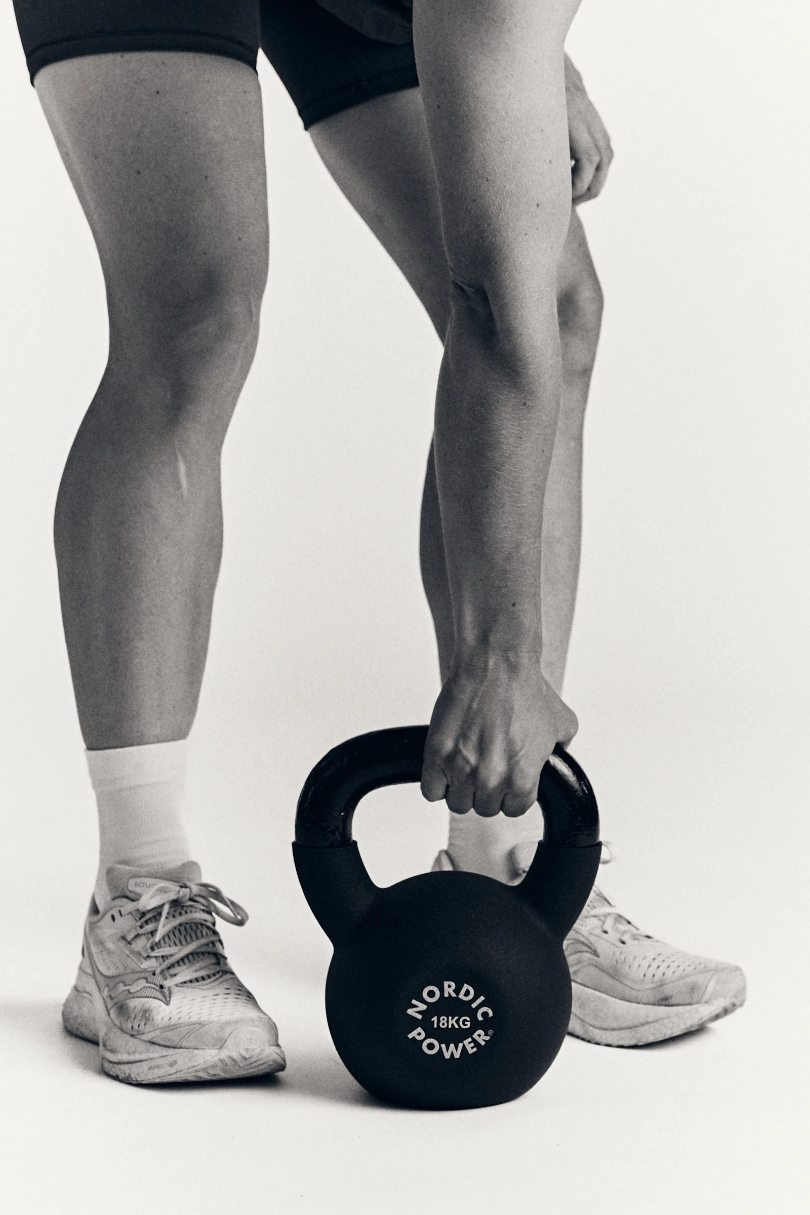 Kettlebell løftes fra gulvet, sort-hvid studiefoto